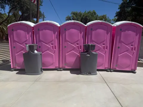 Row of event porta potties with two hand washing stations in front