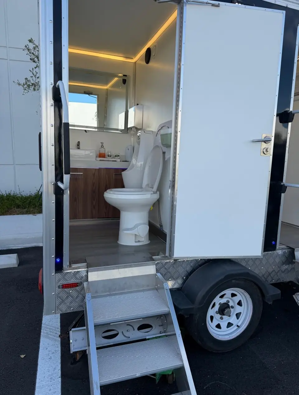 Restroom trailer with open door showing a lit vanity